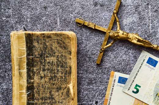© Marcin Łazarczyk - stock.adobe.com Foto: Kreuz, Buch und Geldscheine