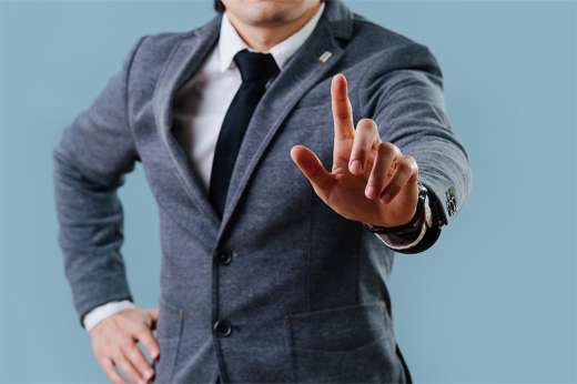 © zzzdim - stock.adobe.com Foto: Person mit ausgestrecktem Finger und Krawatte